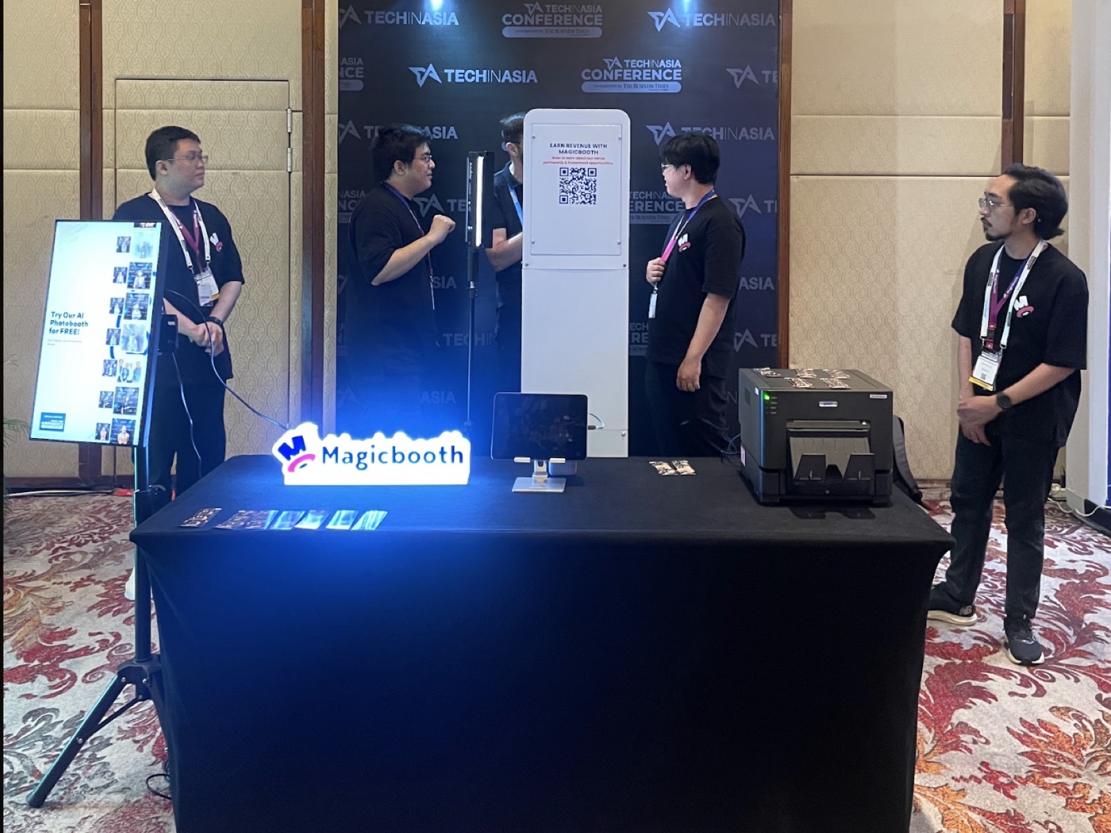 Compact MagicBooth conference setup with operator table, QR screen, booth, and printer