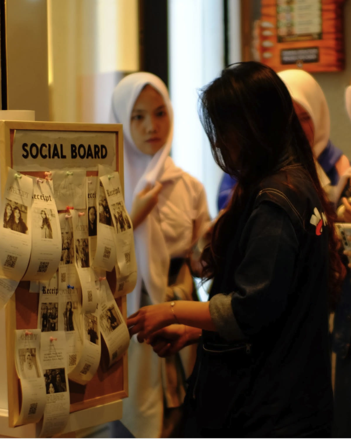 Close-up ekspresi pengunjung setelah menerima receipt; receipt berada di foreground dan booth masih terlihat samar di belakang.